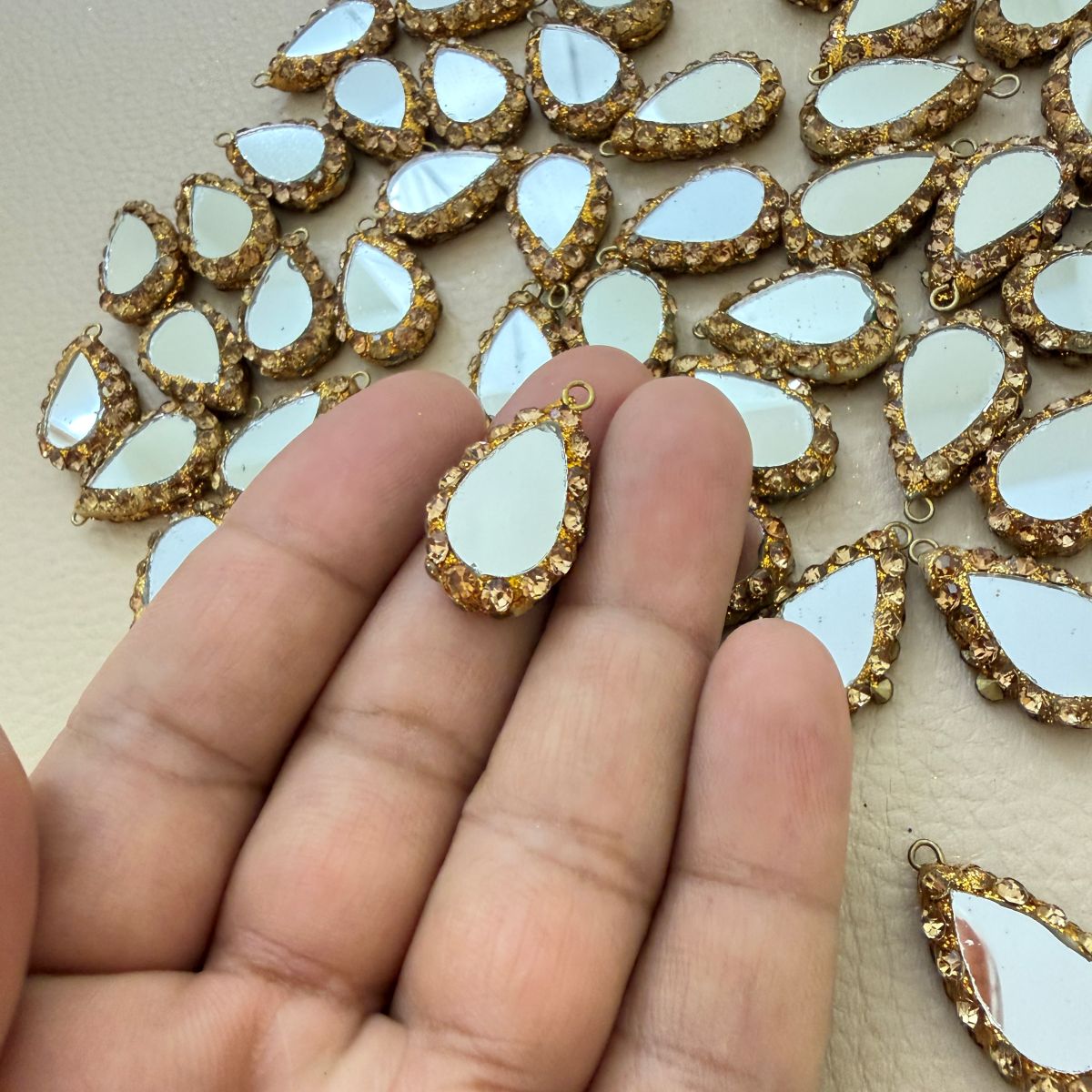 Close-up of gold and champagne teardrop mirror tassel charm