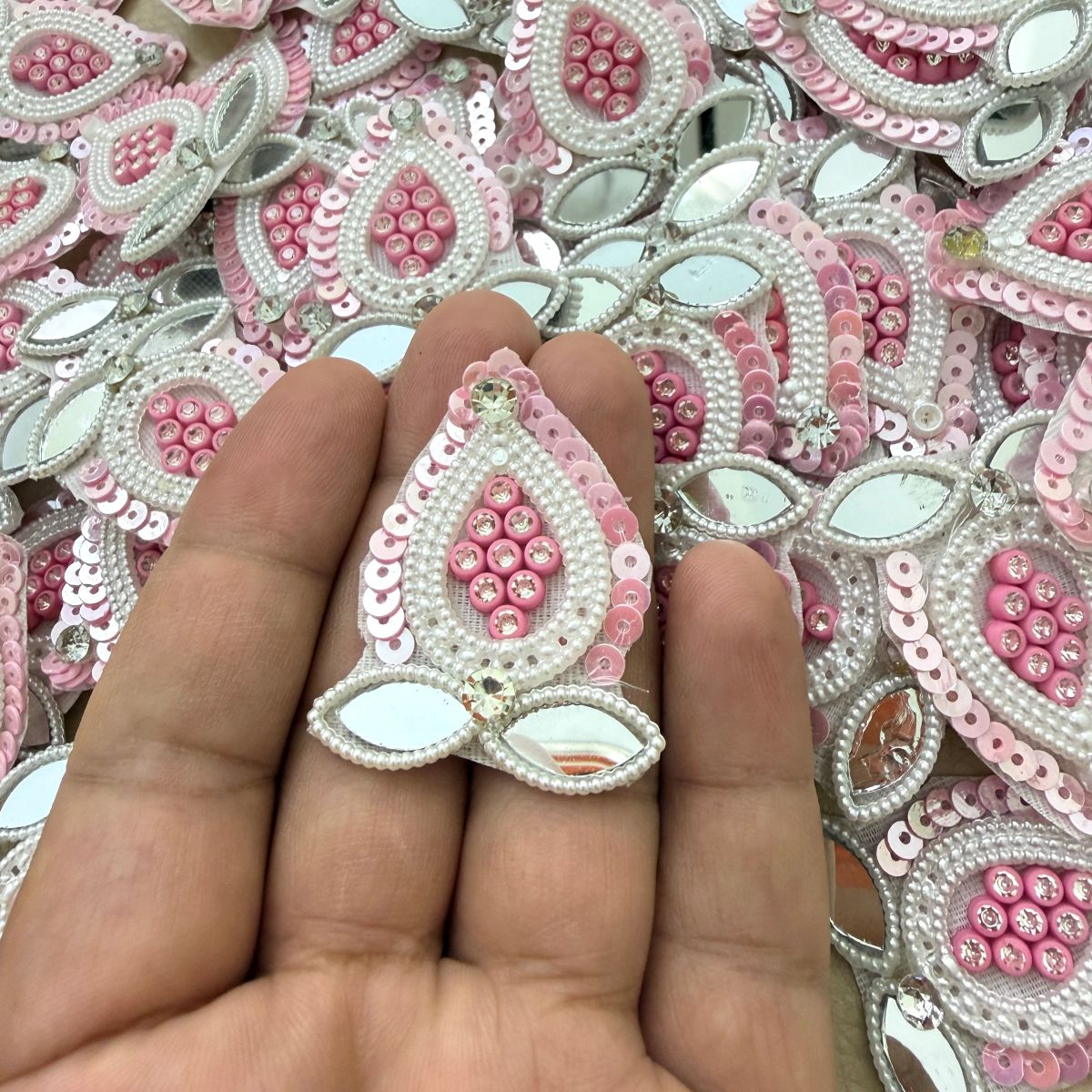 Pink sequin and mirror patch held in hand showing beadwork and clear stone details