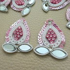 Close-up of pink teardrop patches with pearl-look bead borders and two leaf-shaped mirror accents