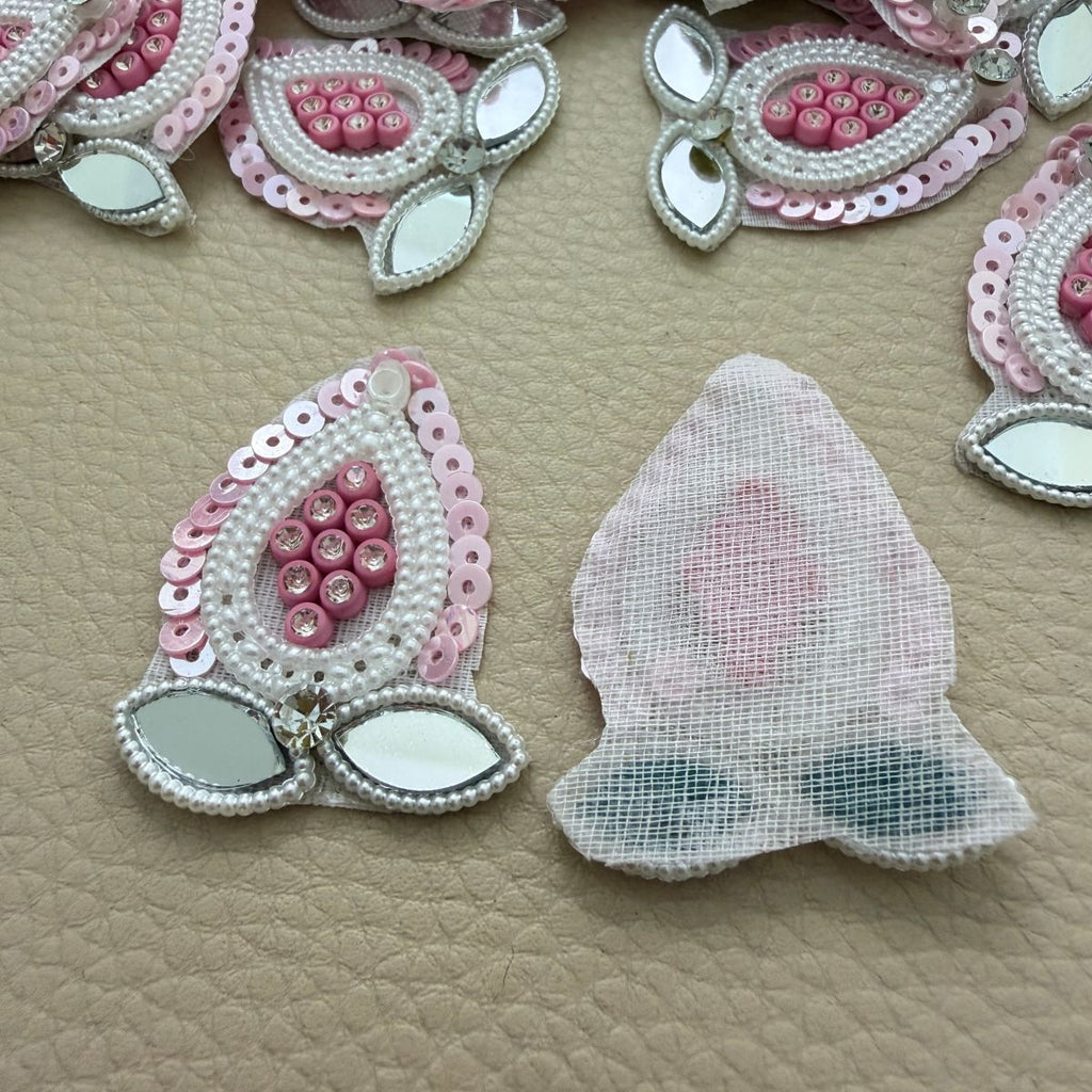 Front and white mesh backing of pink teardrop mirror and pearl-look patch