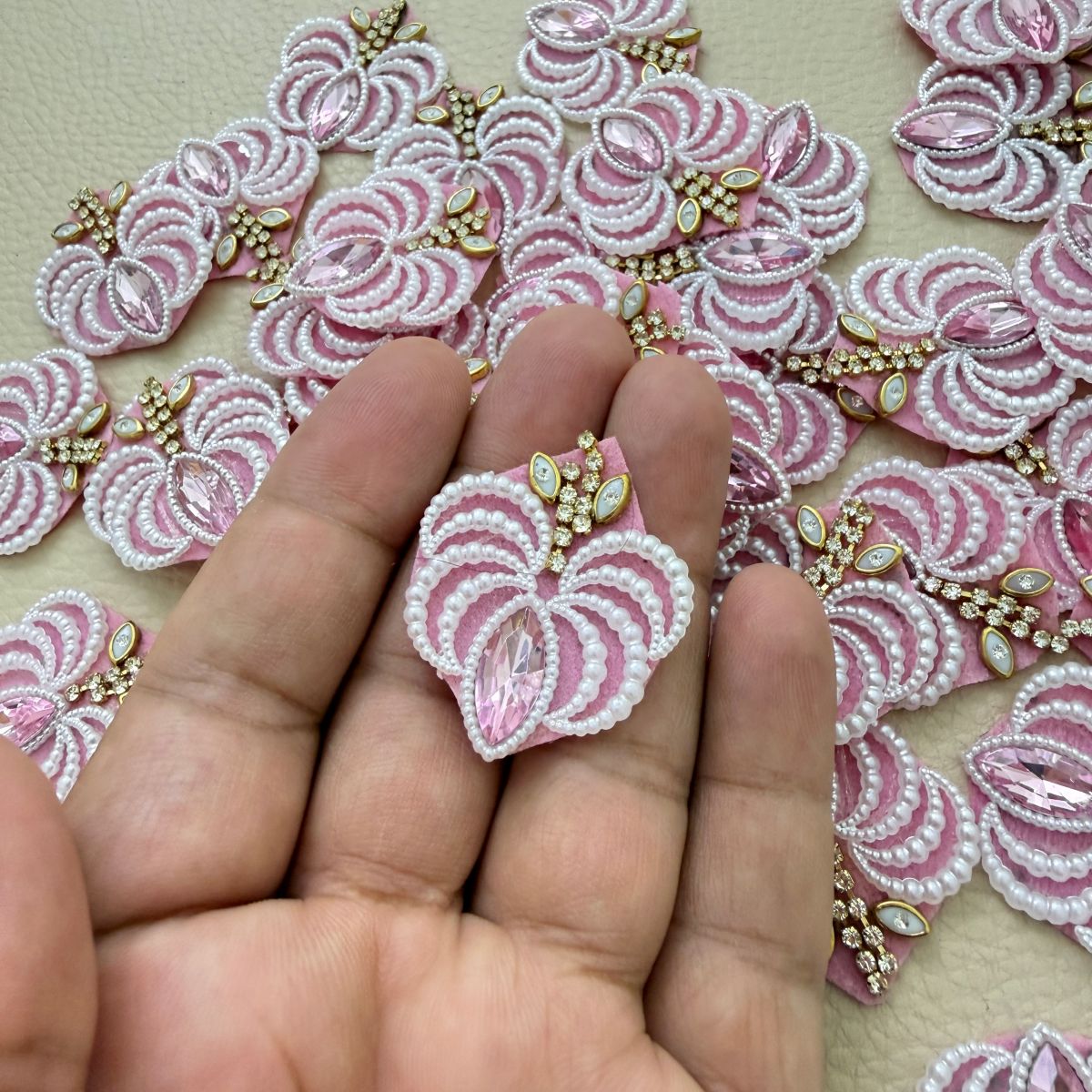 Pink marquise stone and white pearl-effect fan patch held in hand
