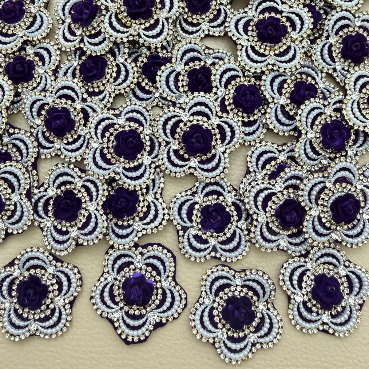 Purple rose flower patch with white pearl-look beads and clear rhinestones shown in hand
