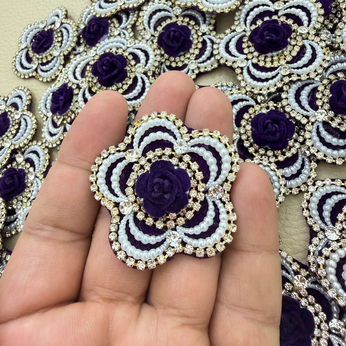 Close-up of purple floral patches with raised rose centres and rhinestone borders