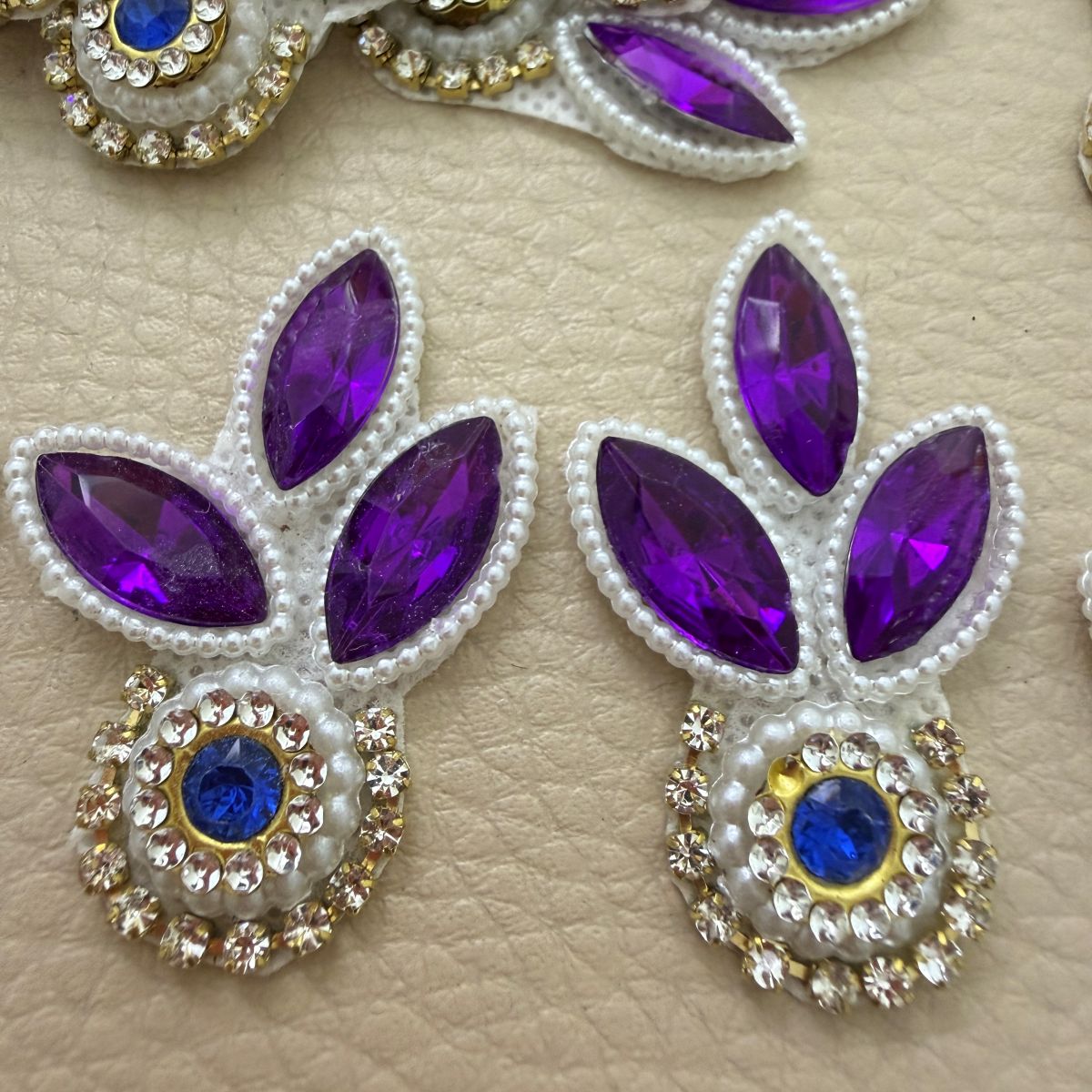 Purple leaf and blue stone patch held in hand showing pearl-look beads and clear stone detailing