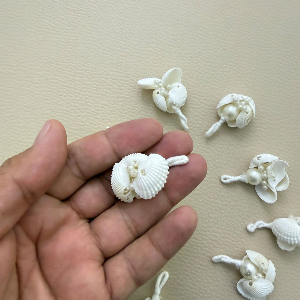 White shell tassel held in a hand to show its size and shell details