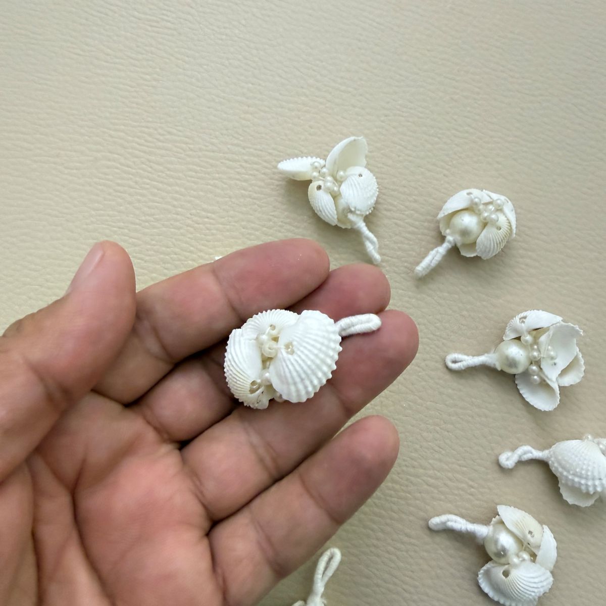 White shell tassel held in a hand to show its size and shell details