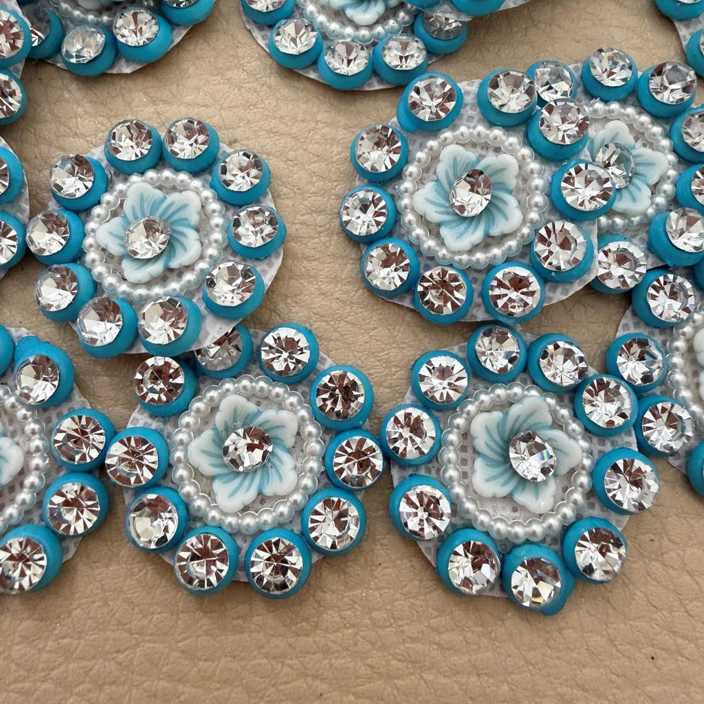 Blue flower appliques shown in a hand for scale