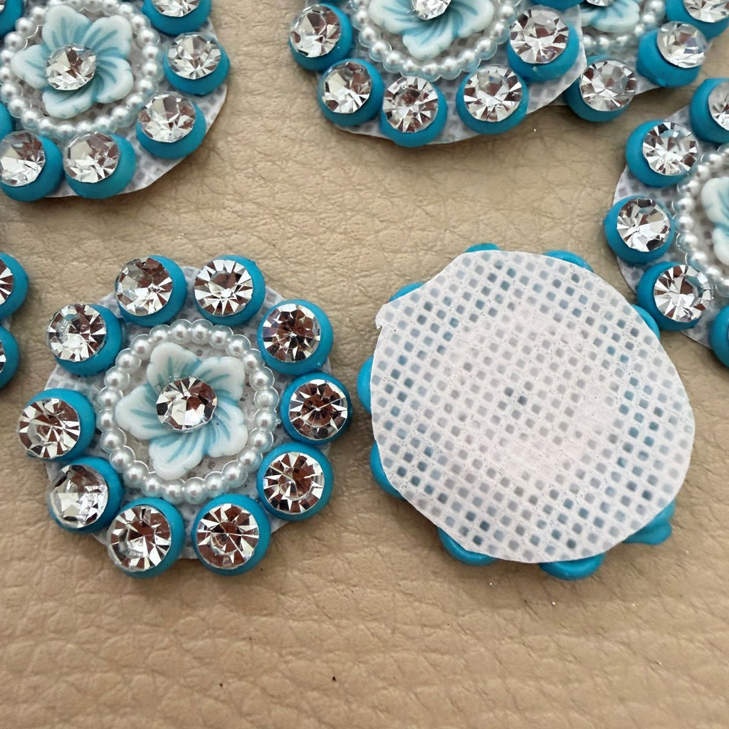 Close-up of pale blue flower centers with clear rhinestones, pearl-look beads and turquoise borders