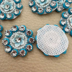 Close-up of pale blue flower centers with clear rhinestones, pearl-look beads and turquoise borders