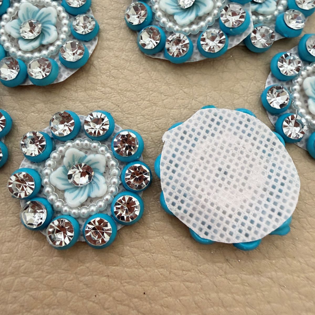 Close-up of pale blue flower centers with clear rhinestones, pearl-look beads and turquoise borders