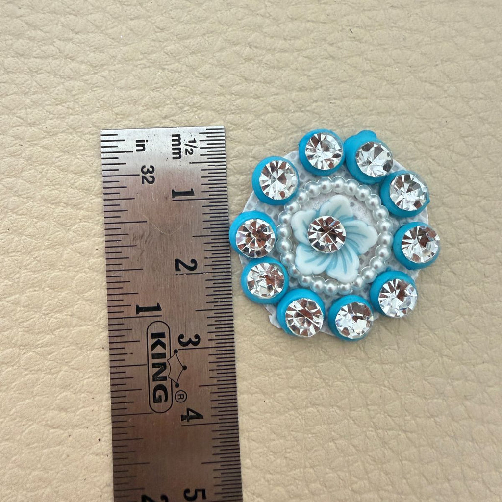 Blue flower rhinestone applique beside a ruler, approximately 3 cm across