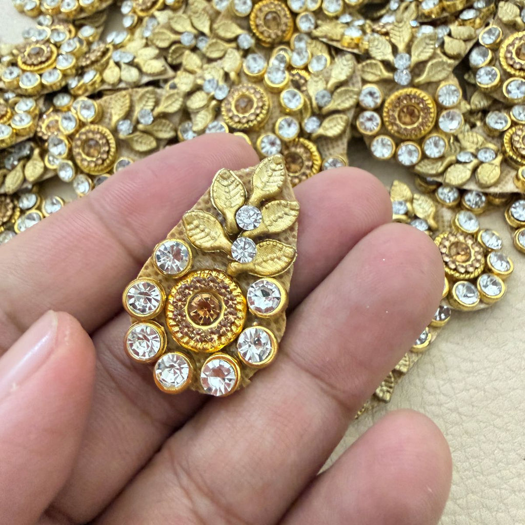 Gold leaf and rhinestone teardrop applique held in a hand