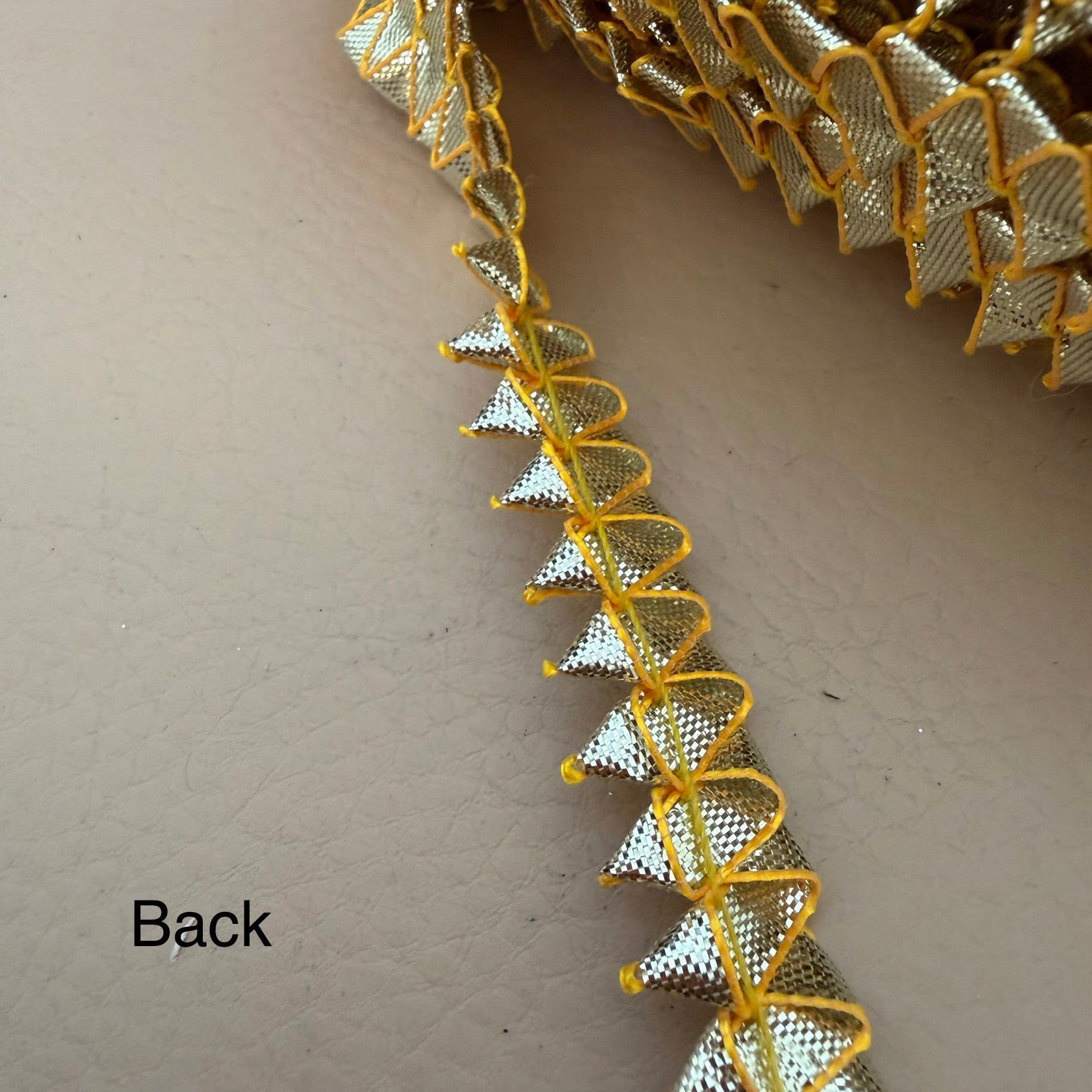 Close-up of decorative gold and silver trim on a beige background