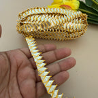 Decorative gold and white ribbon held by a hand with a blurred background