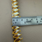 Decorative trim with gold and silver pattern on a gray background, measured by a King ruler.