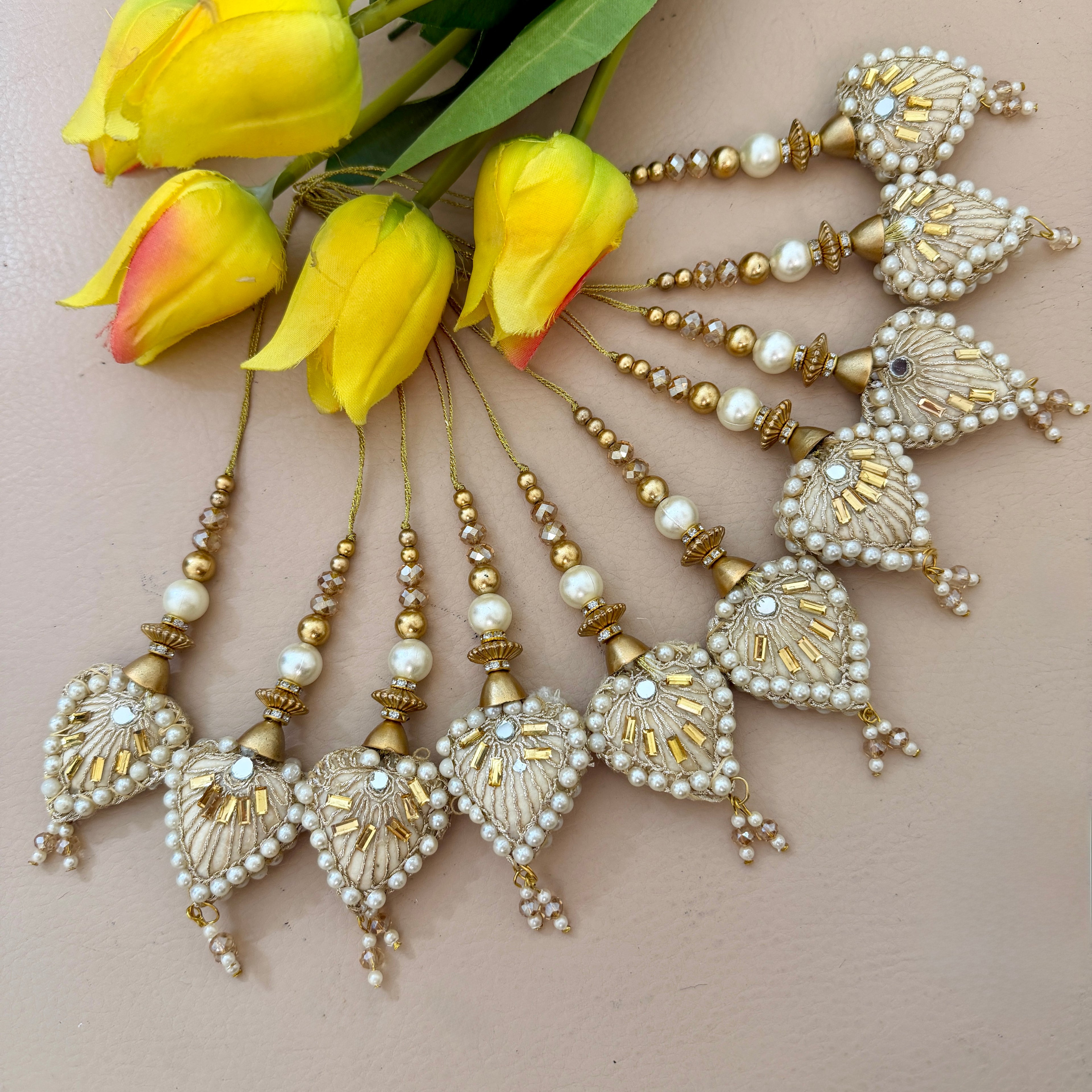 Decorative hair accessories with pearls and gold accents on a beige background with yellow tulips.