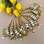 Decorative gold hair accessories with mirror details on a beige background with yellow flowers.