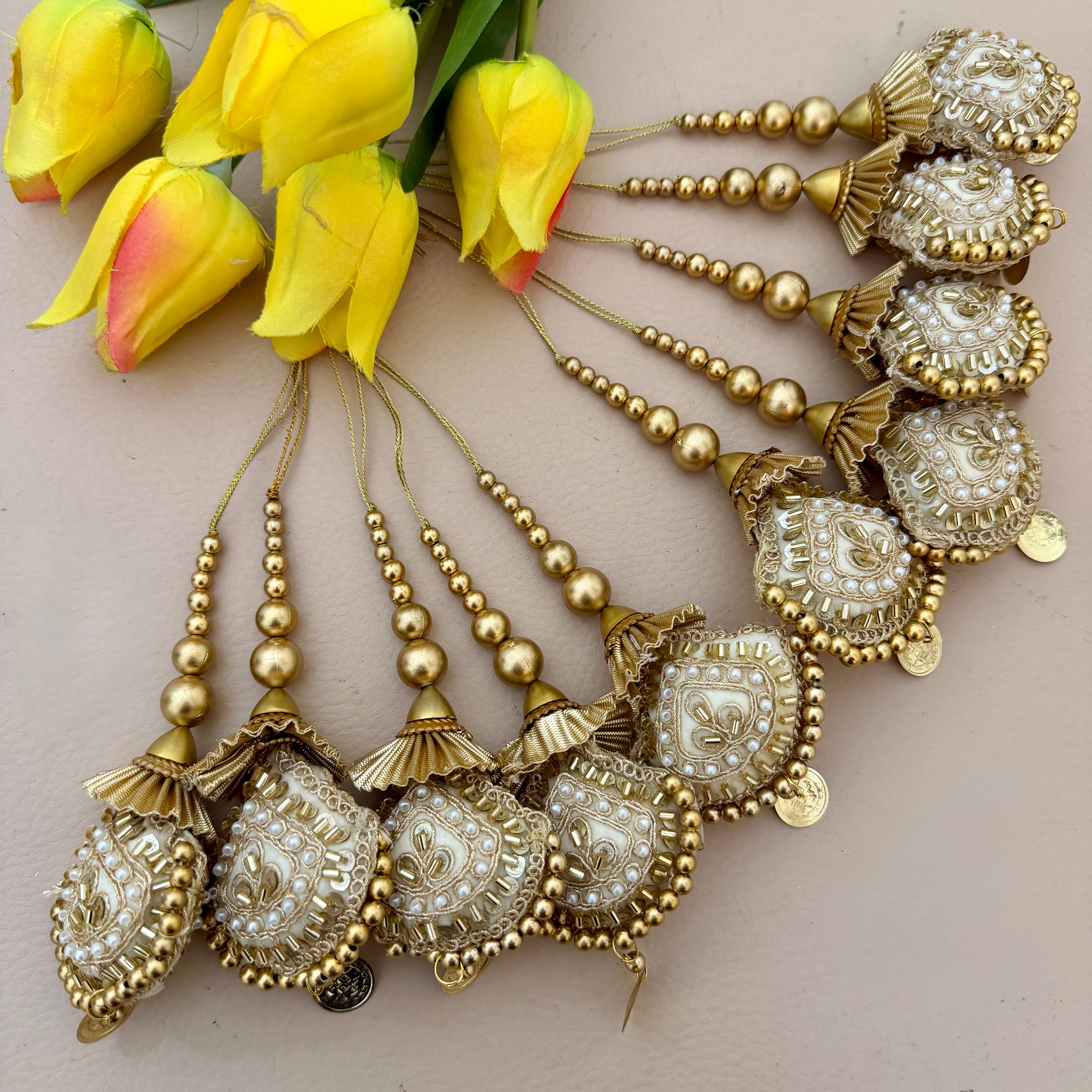 Decorative gold and pearl necklace with yellow tulips on a beige background