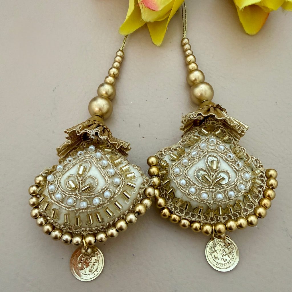 Pair of gold and pearl earrings on a light background
