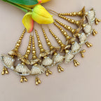 Decorative gold and white earrings with yellow flowers in the background