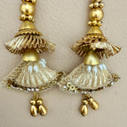 Pair of gold earrings with intricate designs on a beige background