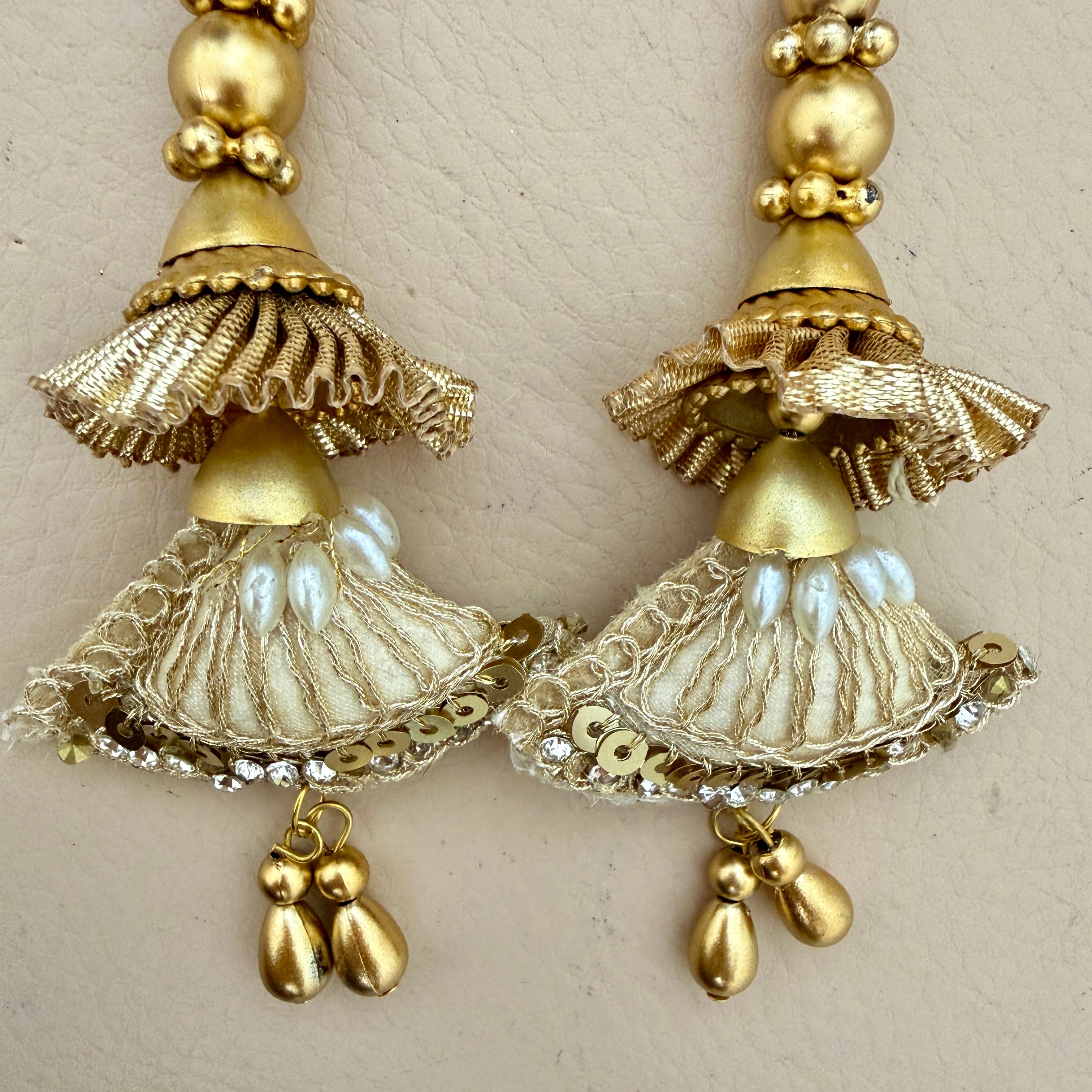 Pair of gold earrings with intricate designs on a beige background