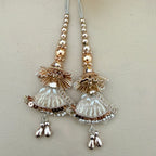 Pair of decorative earrings with gold and silver elements on a light gray background