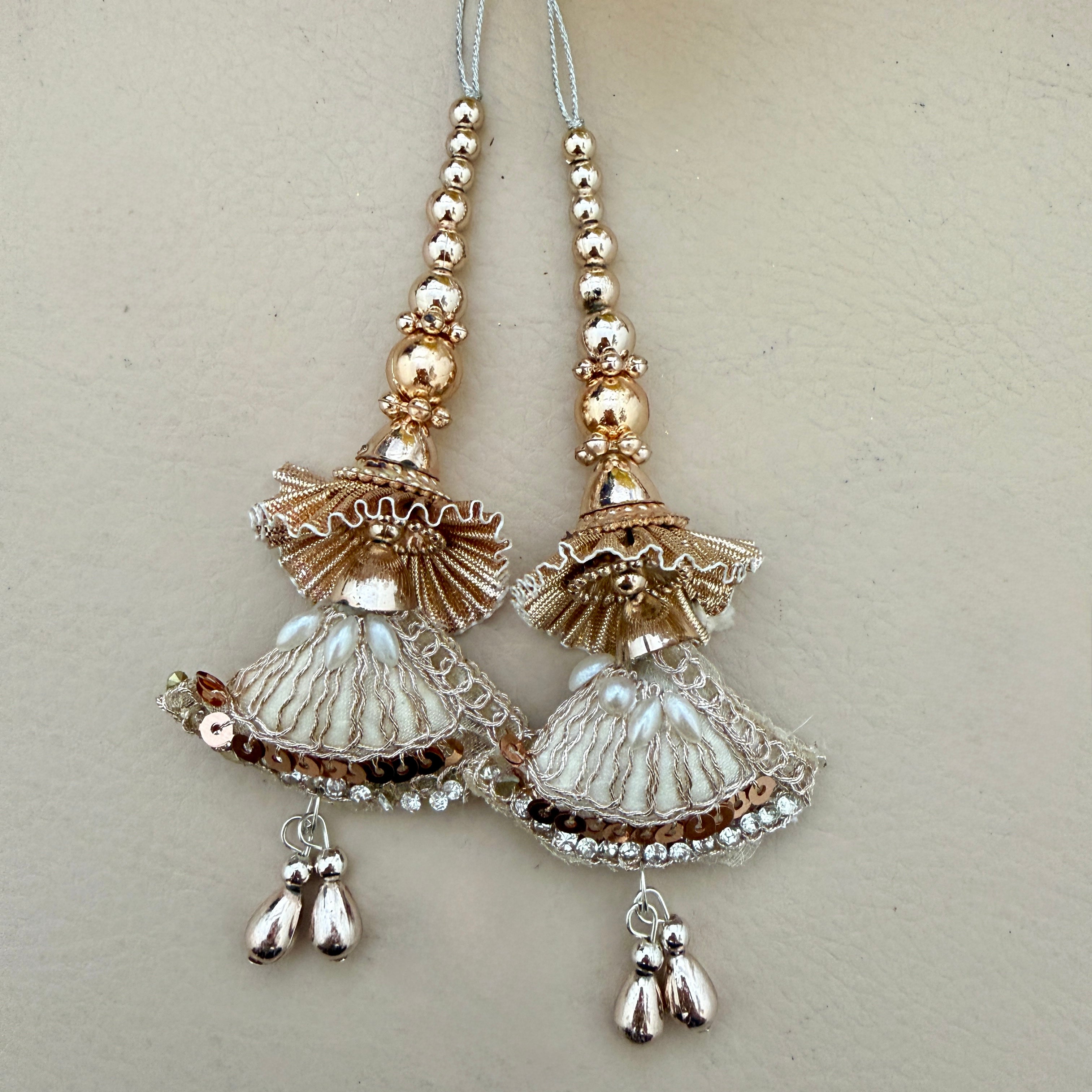 Pair of decorative earrings with gold and silver elements on a light gray background