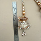 Decorative hanging charm next to a ruler on a beige background