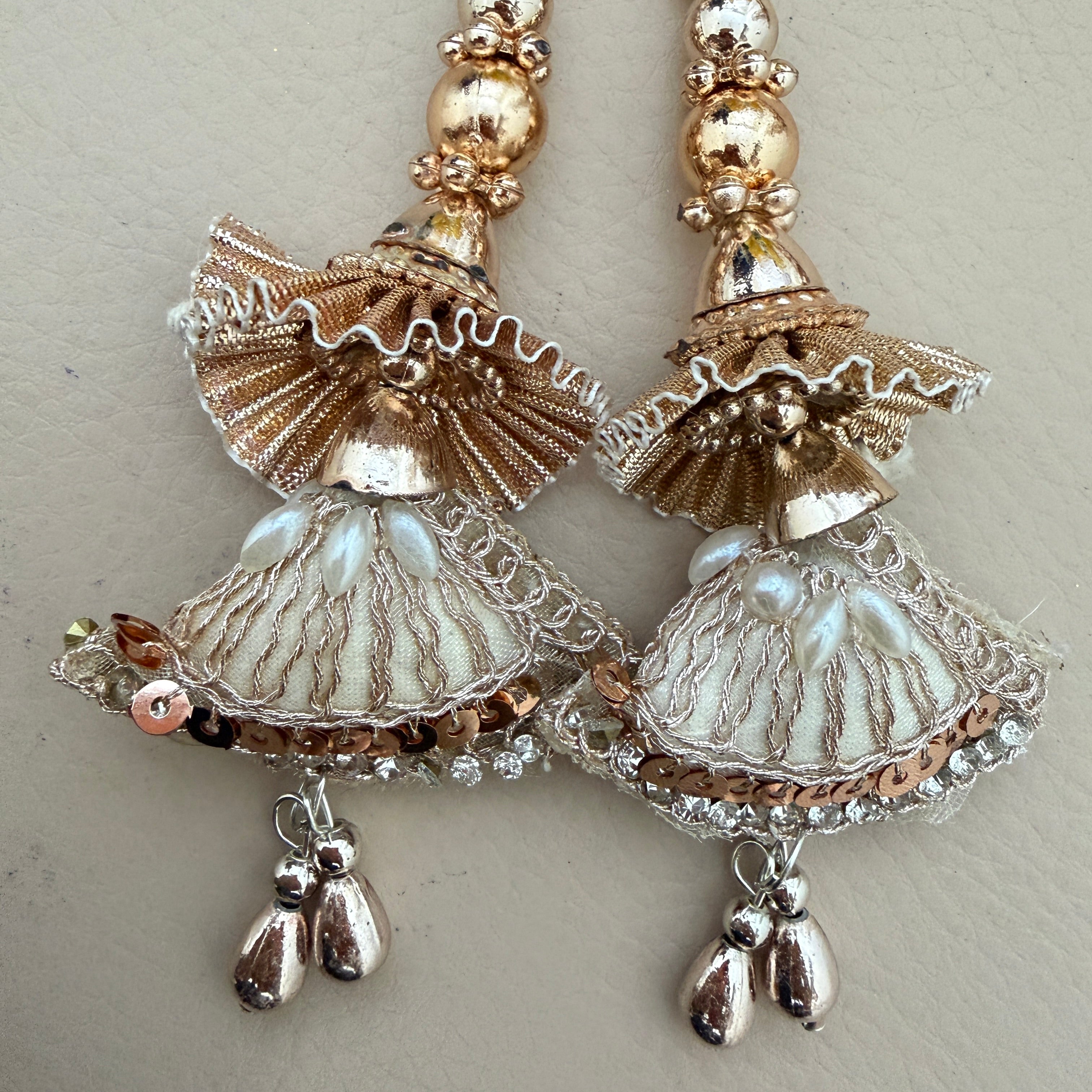 Decorative earrings with gold and silver elements on a light background