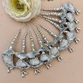 Silver jewelry set with shell-like designs on a beige background
