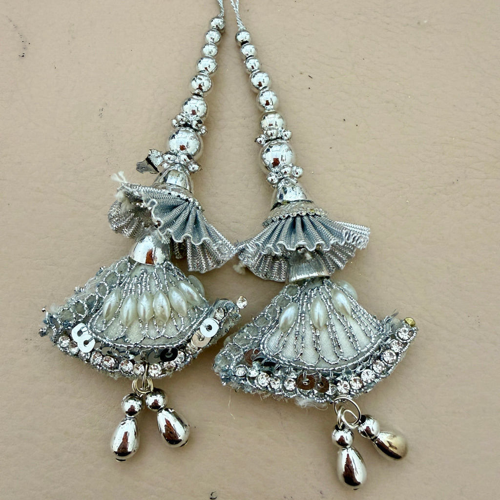 Pair of silver and white earrings on a beige background
