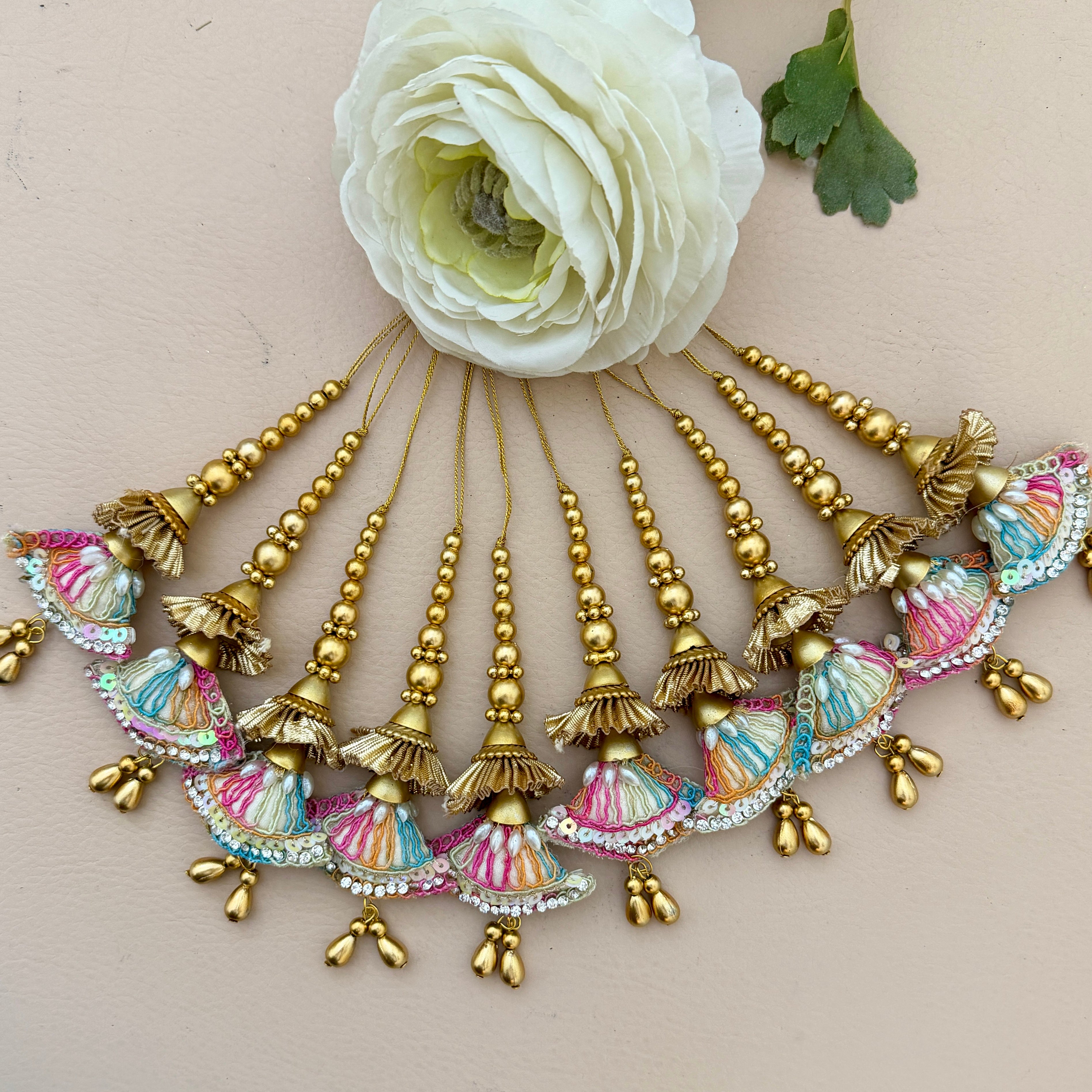 Decorative hair accessories with colorful tassels and beads on a beige background with a white flower.