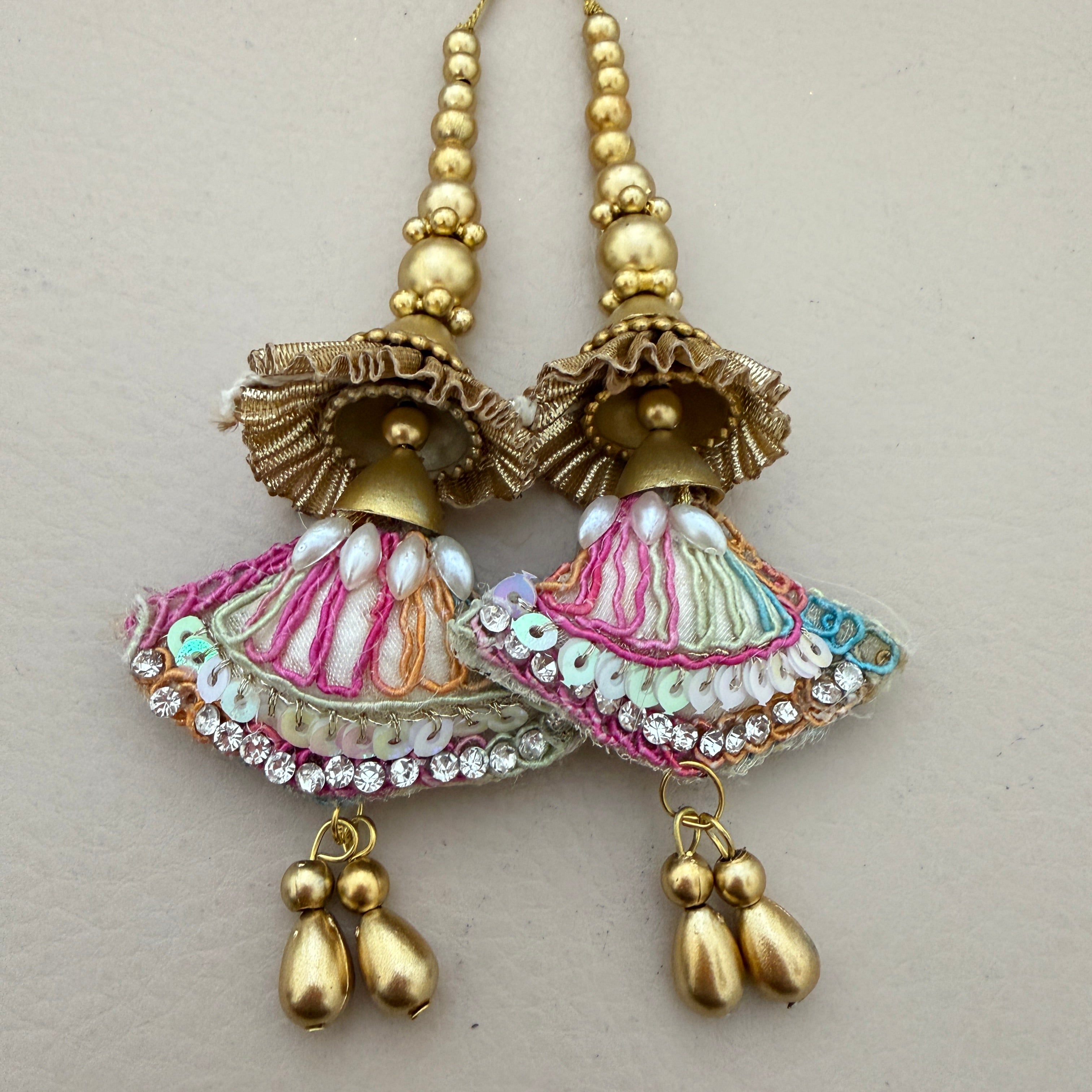 Decorative earrings with gold, pink, and white details on a light gray background