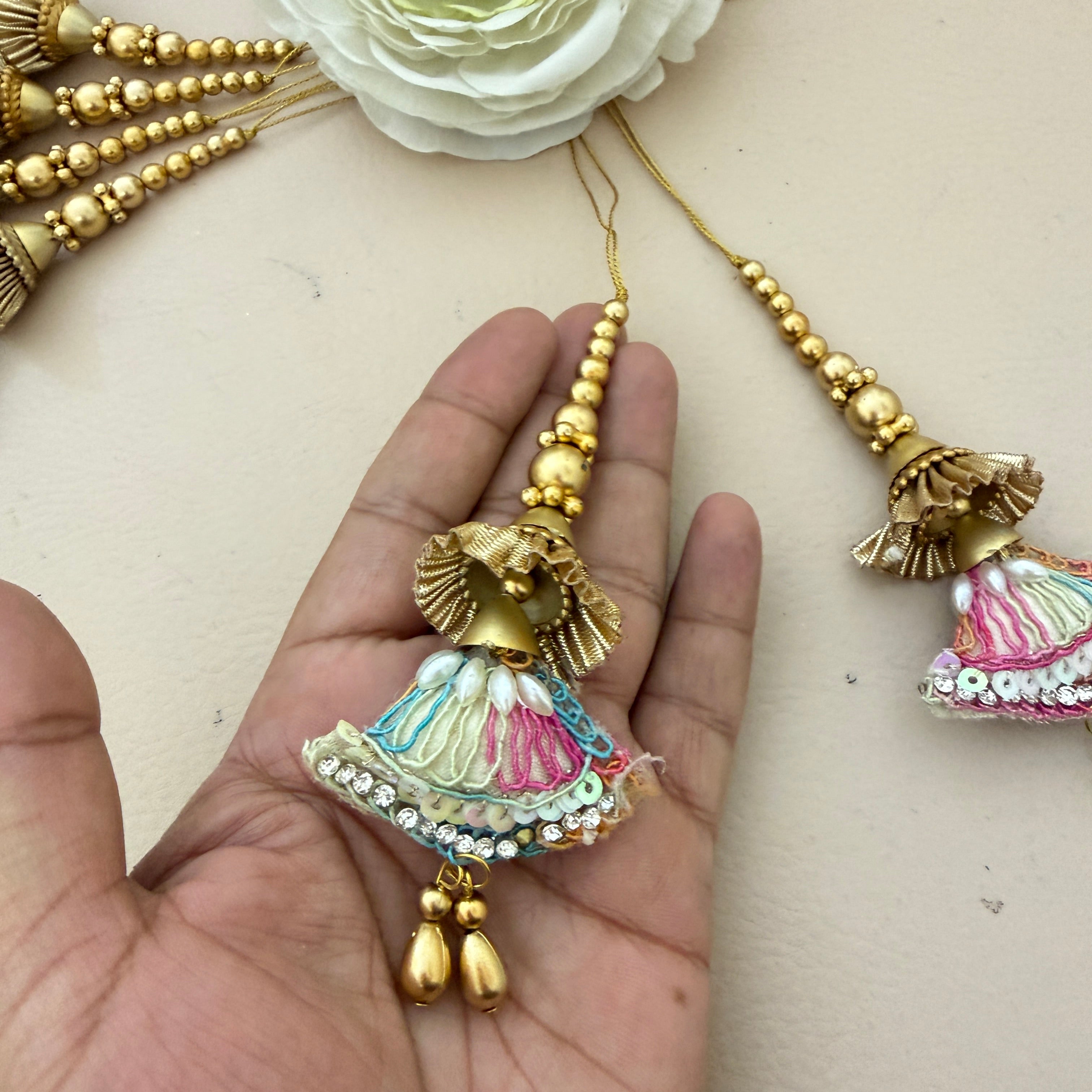 Decorative multicolored tassel held in a hand with a beige background