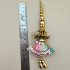 Decorative tassel with colorful embellishments next to a ruler on a beige background
