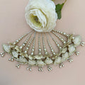 Decorative headpiece with shell-like designs and beads on a light pink background with a white flower.