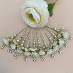 Decorative headpiece with shell-like designs and beads on a light pink background with a white flower.