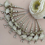 Decorative hairpiece with shell-like elements and beads on a beige background with a white flower.