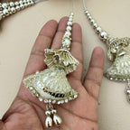Decorative silver bell charm held in a hand against a neutral background