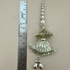 Decorative silver jhumka earring with a ruler for scale on a beige background