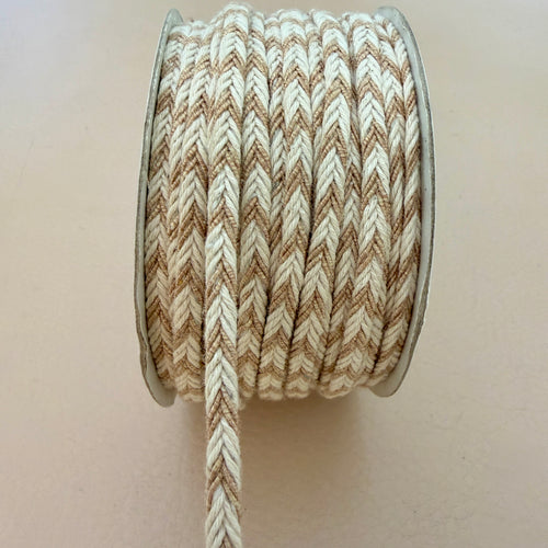 Spool of brown and beige braided cord on a plain background