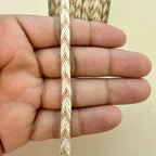 Hand holding a piece of braided rope against a plain background