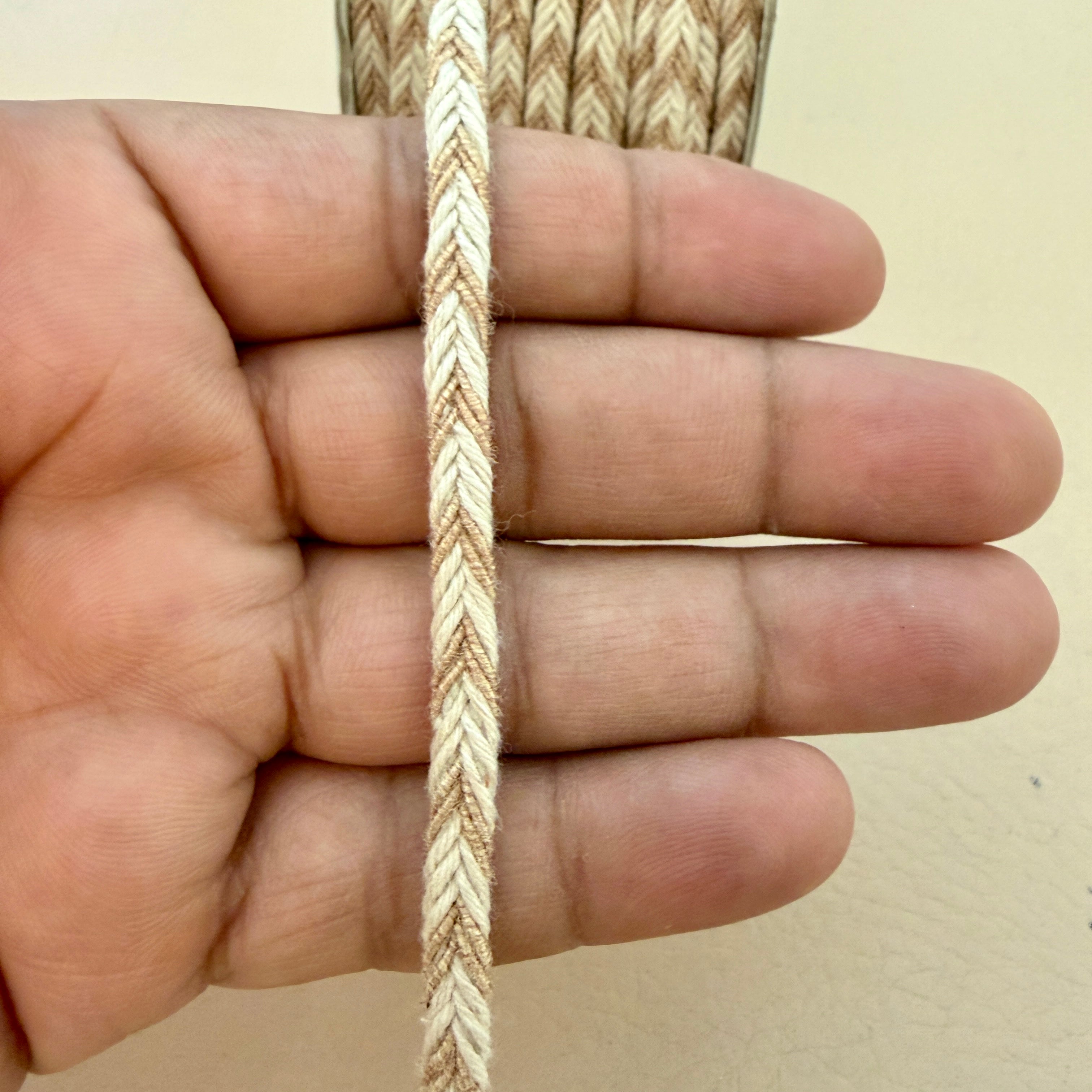 Hand holding a piece of braided rope against a plain background
