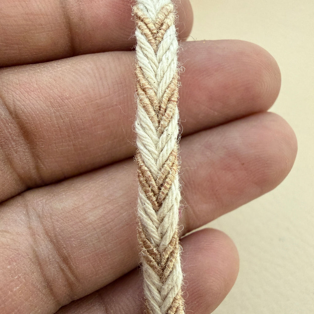 Close-up of a hand holding a braided beige and white cord.