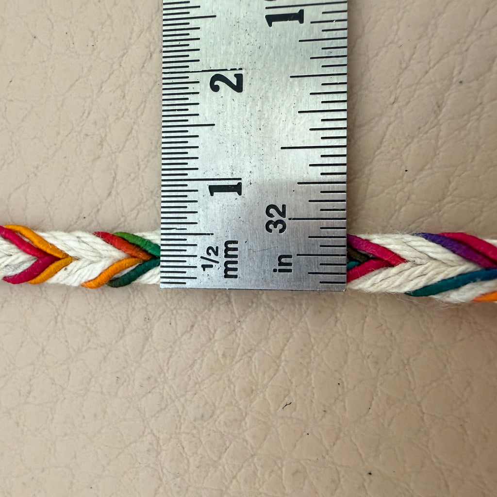 Colorful braided cord with a ruler for measurement on a beige leather background