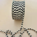 Spool of black and white striped rope on a beige background