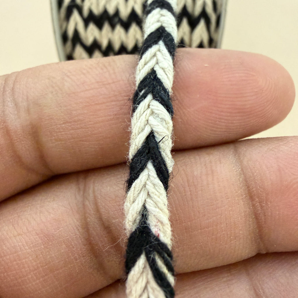 Close-up of a hand holding a black and white braided cord.