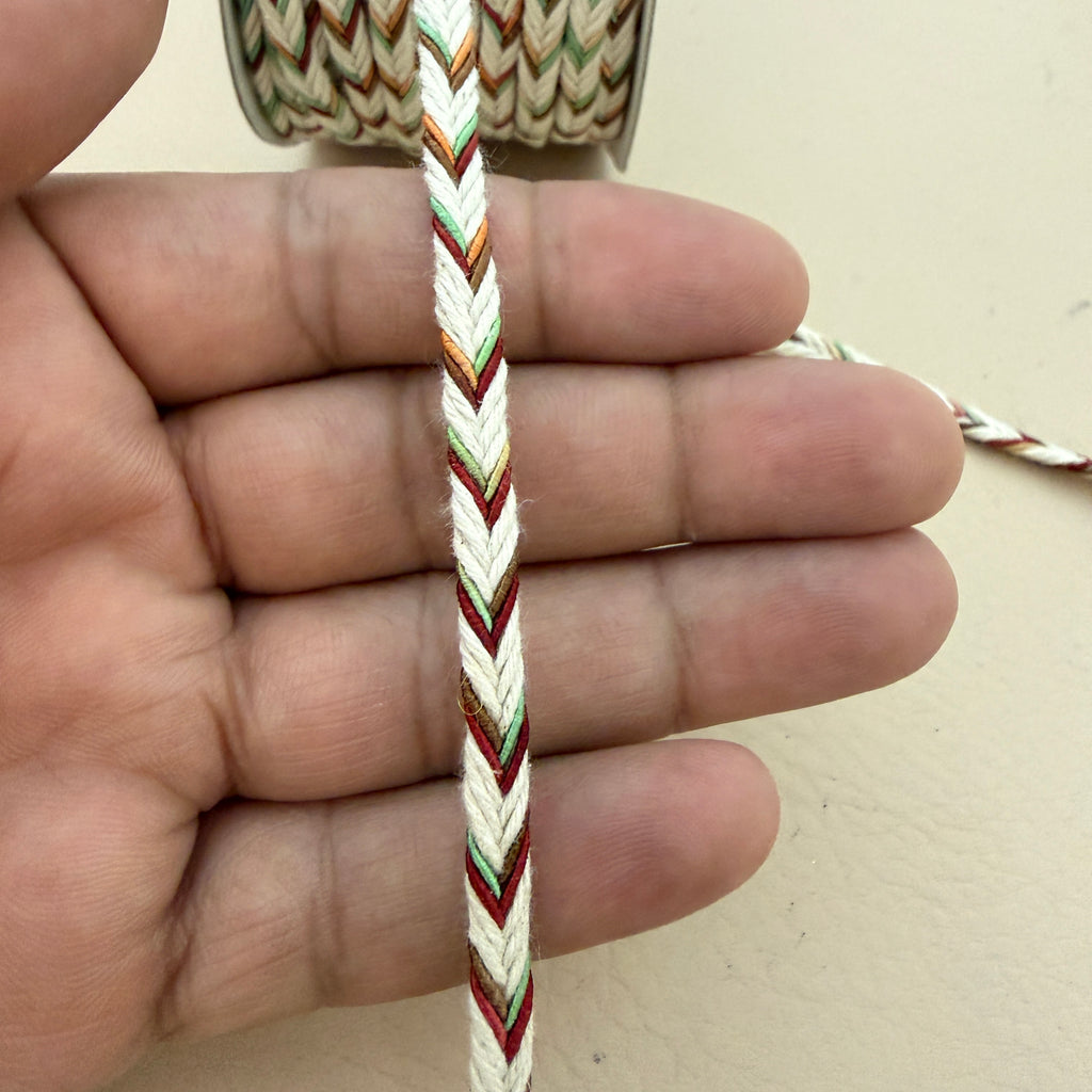Hand holding a multicolored braided cord against a neutral background
