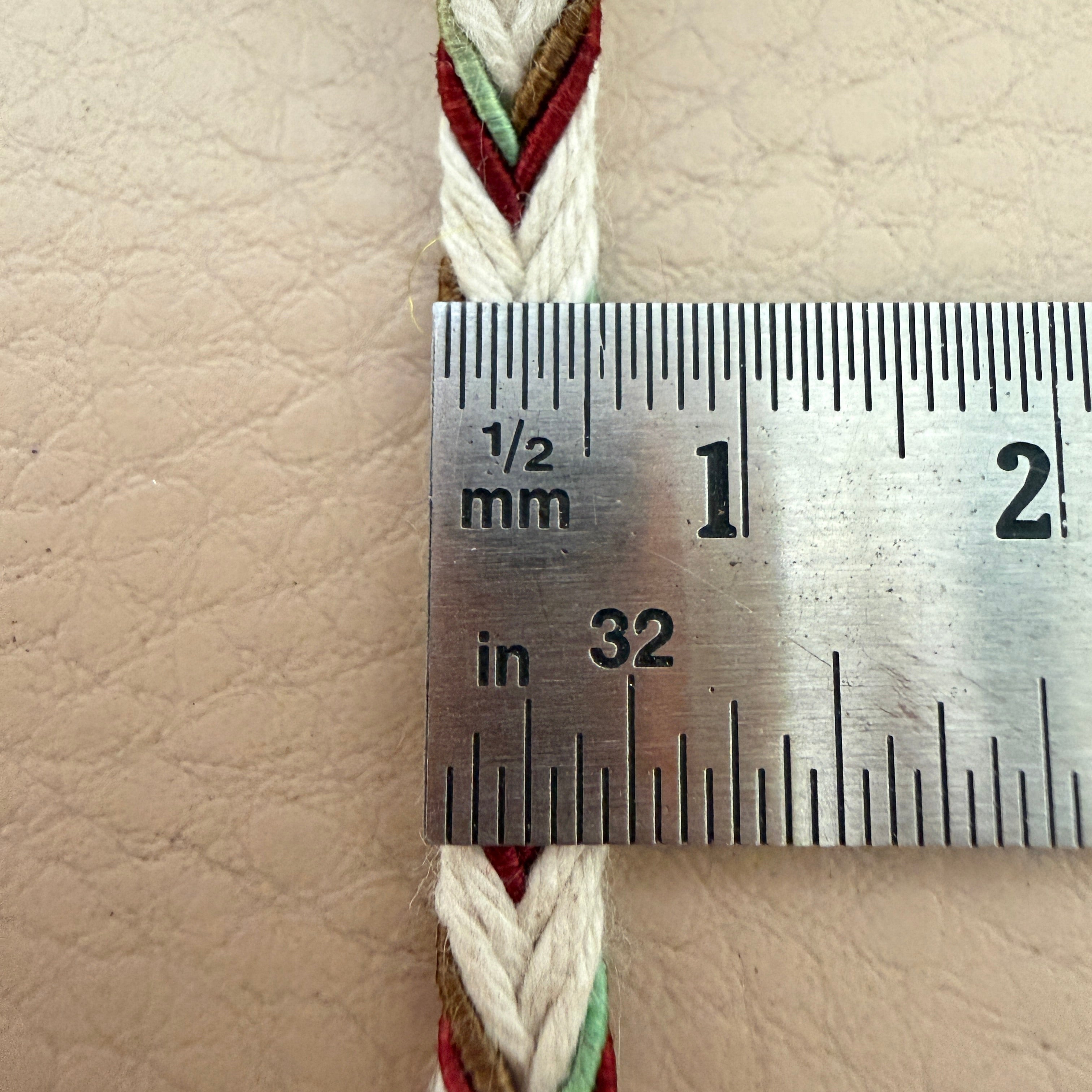 Close-up of a measuring ruler on a woven bracelet with a beige background